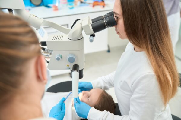 Dentystka używa mikroskopu, co pokazuje skuteczność podtlenku azotu w leczeniu.