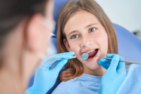 Dentysta pokazuje metody zapobiegania próchnicy u dzieci podczas wizyty kontrolnej.
